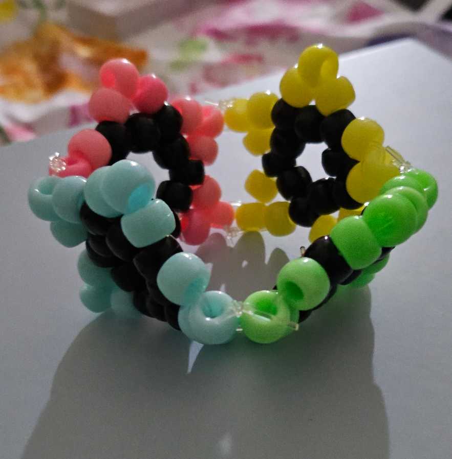 A kandi cuff made of four star charms in pink, yellow, blue, and green.