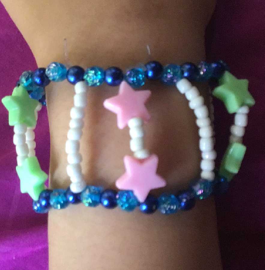 Long bar cuff with two alternating translucent and opaque singles, connected by star and white beads.