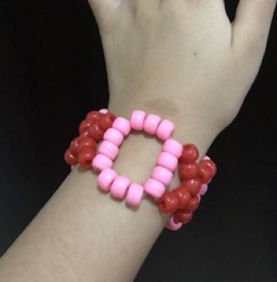 A kandi cuff made of XOXO's. The X's are red, and the O's are pink.